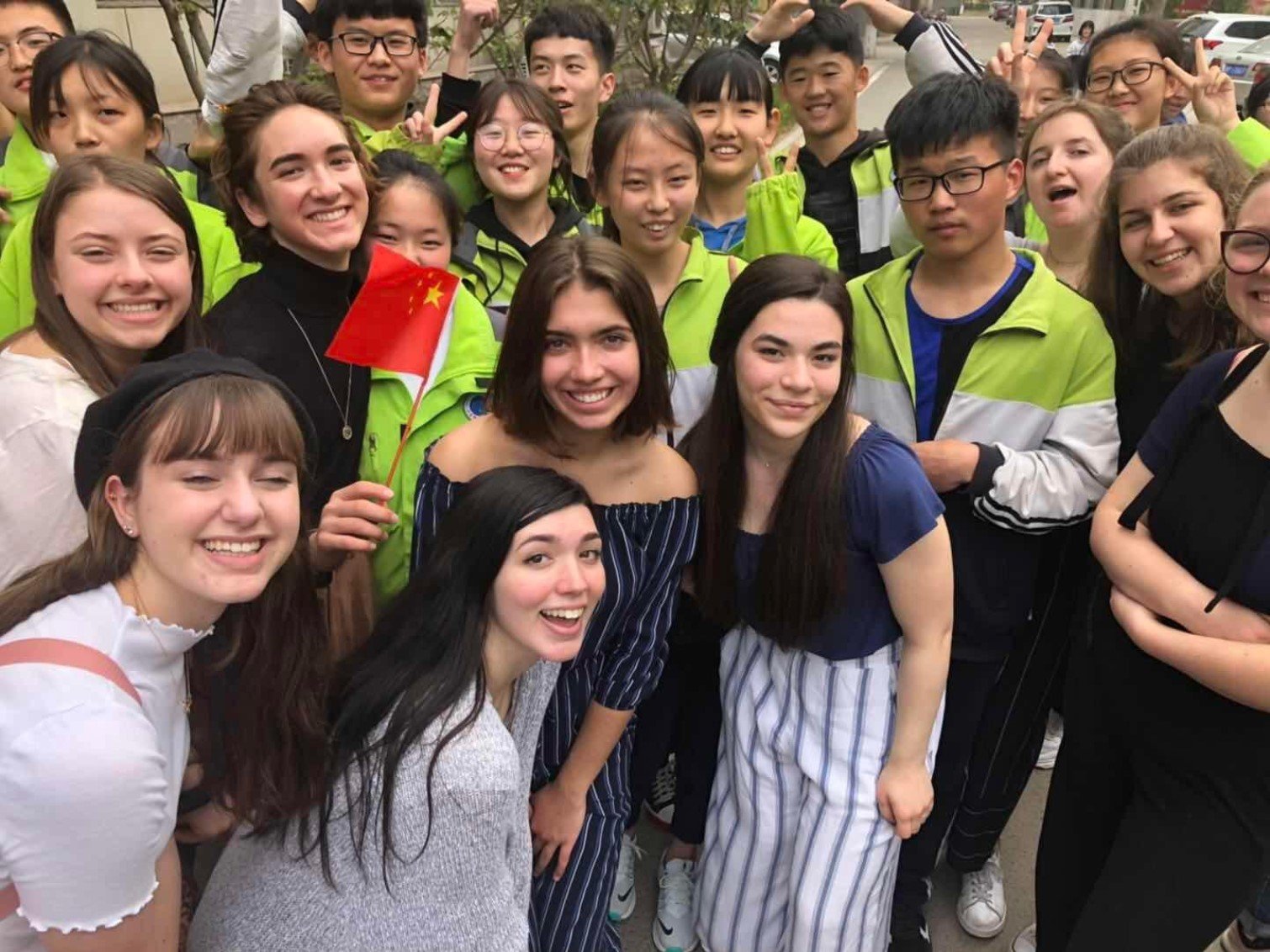 Multiple members of the Student Study Tour group take a picture with students from China. 